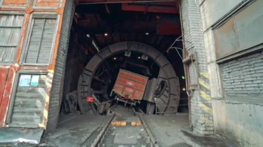 Vagon bahşişçisi içinde bir vagon kömürle dönüyor ve bitkinin üzerine fosil döküyor. Kamera ileri doğru hareket ediyor. Yakın plan..