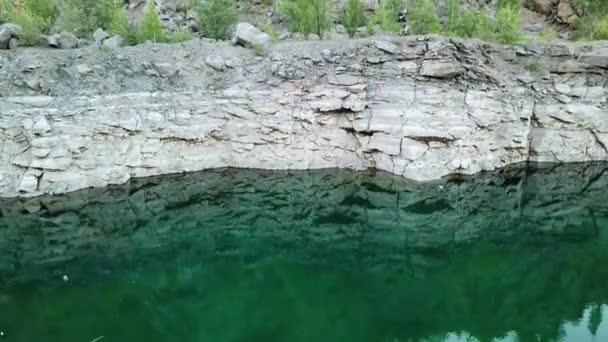 靠近石坡的干净的水底和走在石坡上的游客 空中拍摄岩石峡谷与漫游者在户外 移动底部向上 — 图库视频影像