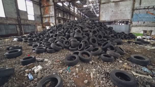 車のタイヤの束は 建物の窓に穴のある放棄された高い格納庫にあります 内部の古い工場の眺め — ストック動画