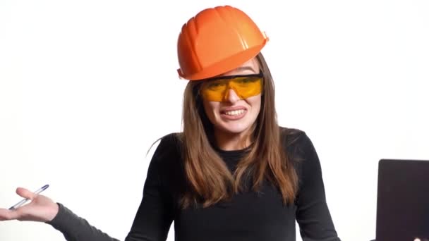 身穿黑色套头衫 头戴明亮头盔的快乐的女工程师谈论着生意 她拿着一支白色背景的文件夹和一支笔 摆出姿势 手里拿着一支笔 — 图库视频影像