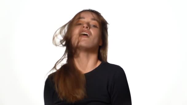 茶色の髪の情熱的な女性は スタジオの白い背景に彼女の髪を後ろに傾ける — ストック動画