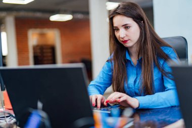 Konsantre kadın geliştirici modern ofiste bir bilgisayar üzerinde çalışıyor. Çekici genç kadın programcı bilişim şirketinde yeni teknolojiler geliştiriyor. Yüksek kaliteli resim.