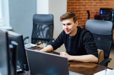 Yaratıcı ofiste masa başında çalışan bir adam. Modern iç mekan. Program geliştirme kavramı.