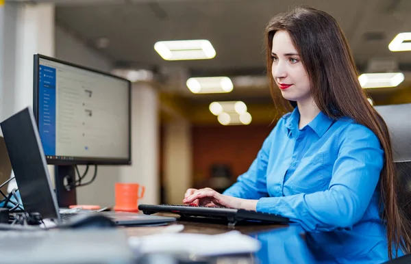 Başarılı bir kadın programcı çalışırken masada bir bilgisayarla oturuyor. Yazılım şirketinde monitöre bakan güzel bir kadın..