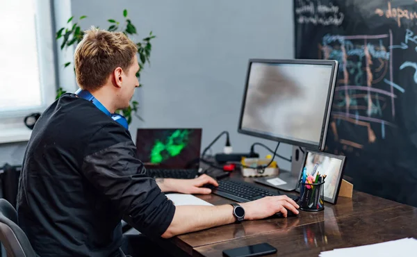 Mužský programátor pracující na stolním počítači v blízkosti monitoru v kanceláři společnosti pro vývoj softwaru. Programování a kódování webových stránek. — Stock fotografie