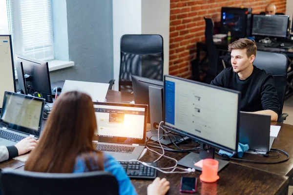 Modern bir ofiste çalışan iki yönetici. En iyi sonuçlara ulaşmak. Bilgisayarlarda çalışan kendinden emin iki genç insan. İş konsepti.