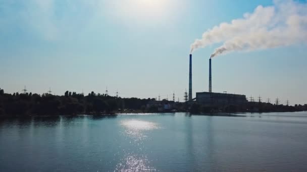 昼間は青い空の下 川の近くの大きな植物への水の近くの空中ビュー 湖岸に2本の大きなパイプを持つ水力発電所 — ストック動画