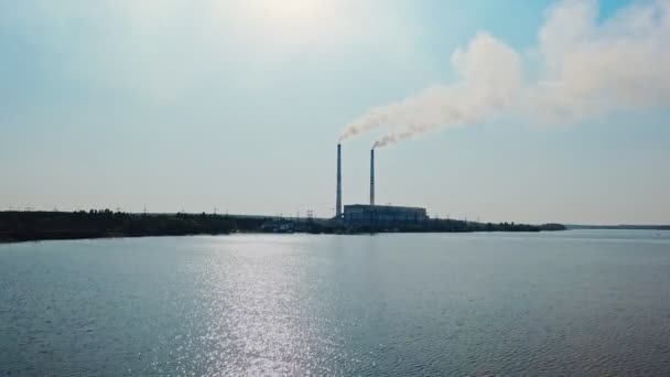 川にある水力発電所を背景に 昼間に水の上で撮影されたビデオ カメラの動きトップダウン — ストック動画
