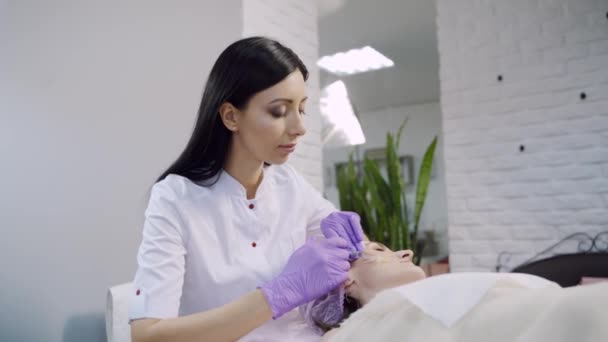 Kosmetička Dlouhými Vlasy Zkontroluje Injekci Zahájí Biorevitalizační Proceduru Tváři Ženy — Stock video