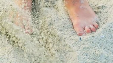 Bir insanın ayakları yaz mevsiminde kumsalda kum karıştırıyor. Kum kıyısı. Denizde dinlen..