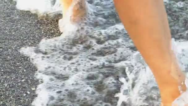 Les gens marchent pieds nus le long du rivage dans le sable humide et les vagues. Promenade maritime près de l'eau. Gros plan .