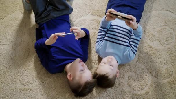 Chłopcy Leżący Podłodze Lekkim Dywanie Grający Gry Komórkach Domu Widok — Wideo stockowe