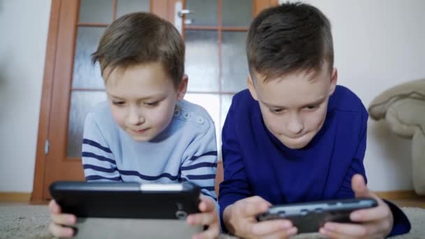 Meninos Felizes Brincando Aparelhos Sem Fio Enquanto Deitados Tapete Casa — Vídeo de Stock