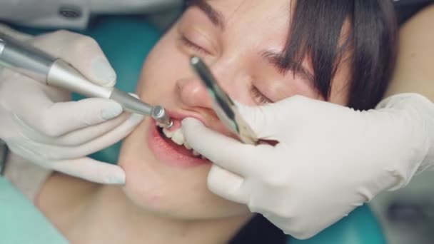 牙科医生在牙科诊所为病人擦亮牙齿 在牙医办公室与病人打交道的一位专家的近视 女病人在看牙医时有些呻吟 — 图库视频影像