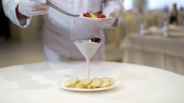 Un serveur sert du fromage cottage dans un grand bol en céramique avec des tomates cerises, des légumes verts et des tranches de citron sur le fond d'une assiette blanche avec cinq tranches rondes de pain sur la table du restaurant .