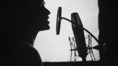 Kayıt stüdyosunda şarkı söyleyen bir kadın. Güzel bir yüzü ve dudakları olan bir kadının profili. Siyah ve Beyaz