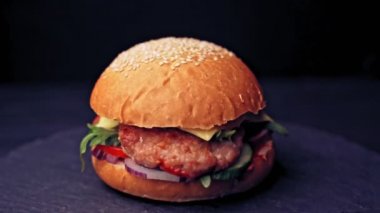 Sığır pirzolası, domates, erimiş peynirli marul, ahşap bir tahtada siyah arka planda döner..
