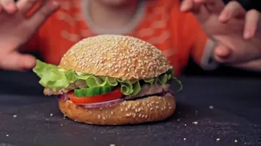 Genç kız fast food restoranında lezzetli hamburgerler yiyor.