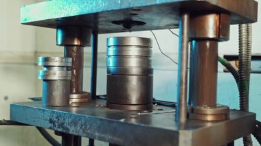 Endüstriyel fabrikada metal parçaları oluşturan bir pres makinesinin yakın çekimi. İşçi basın kalıbına bazı parçalar koyar.