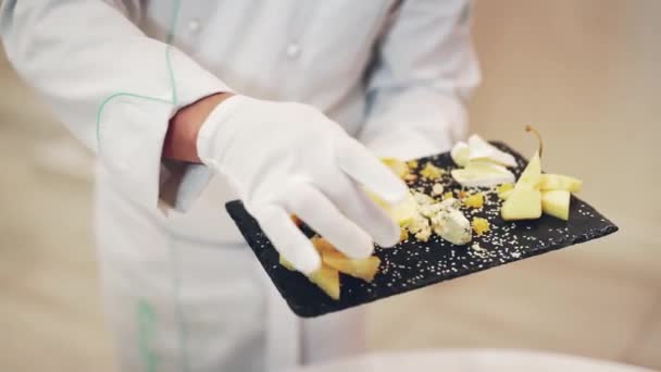 美味的开胃菜不同种类的奶酪装饰一块新鲜柠檬与厨师白色手套 餐厅里的奶酪在黑色表面上的精美呈现 — 图库视频影像