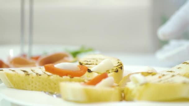 伝統的なカヌーの準備のためのプロのシェフの仕事 チーズ トマト ベコンを皿の上に盛り付けます — ストック動画
