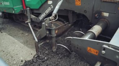 Yol inşaatı yeni asfalt yol yapımında işe yarıyor. Yol yapımı sırasında asfalt döşeyen Paving makinesi. Yakın plan.