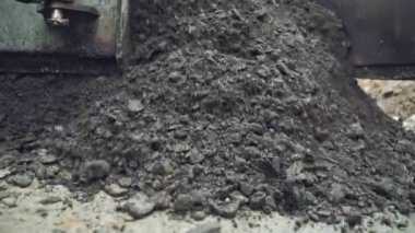 Ağır makineden yere sıcak asfalt dökme işlemi. Yol döşeme işlemi. Yakın plan.