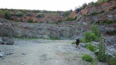 Güzel göl kenarındaki kayalık alanda seyahat eden sportif bir turistin arka manzarası. Aşırı yürüyüşçü taşlı arka planda dışarıda yürüyor..