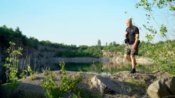 Bald Man Shirt Shorts Trainers Walking Backpack Big Stones Beautiful — Stock Video