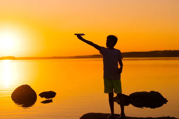 Kleiner Junge Hält Bei Sonnenuntergang Ein Papierflugzeug Der Hand Ein — Stockfoto