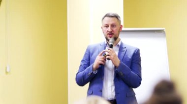 İş konferansında mikrofona konuşan bir konuşmacı tavsiyelerde bulunuyor. Konferans salonunda takım elbiseli bir iş adamı. İş ve Girişimcilik