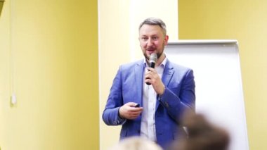 İş konferansı sırasında mikrofonla konuşan bir iş adamının yarım boy portresi. İçerideki konferansta konuşan yakışıklı erkek..