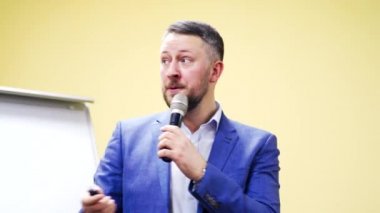 Mavi takım elbiseli profesyonel işadamı konferans salonunda mikrofona konuşuyor. İş konferansında konferans veren yakışıklı adam..