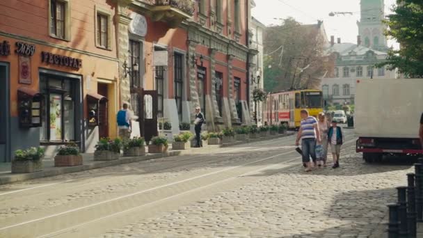古い建物 路面電車や通りの人々とウクライナの都市リヴィウの古代の一部 観光客や古い交通機関でヨーロッパの歴史的中心部の狭い通り — ストック動画