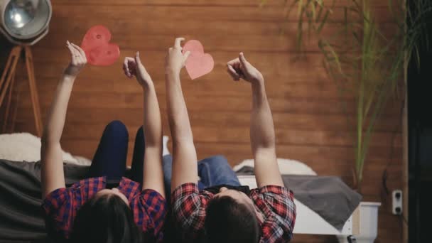 Романтическая Пара Лежащая Постели Играющая Красными Бумажными Сердцами Мужчина Женщина — стоковое видео