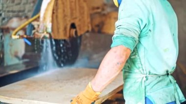 İnsan işçi CNC makinesini kontrol ediyor. Taş levha kesmek için otomatik makine. Sobayı içeride keserken akan su..
