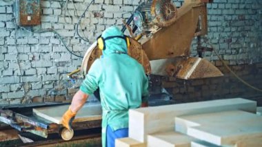Tuğla duvar arka planında otomatik makine olan taş levha kesme işlemi. İş elbiseli adam fabrikada CNC makinesiyle çalışıyor..