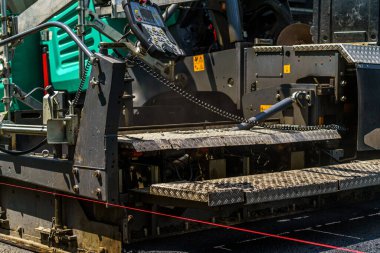 Yeni asfaltı düzleştiriyorum. Asfalt döşeyen, yol tamir eden ağır bir patenci. Seçici odak.