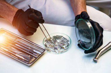 Metalik dişçi aletleri. Diş hekiminin elindeki steril alet..