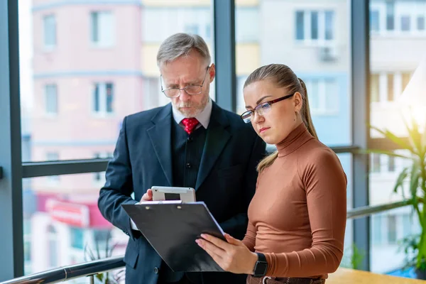 Senior businessman discussing business ideas with the assistance. Mature man and businesswoman in an office. Photo from the business lunch