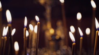 Gece tapınağında bir sürü mum yanıyor. Soyut mum arkaplanı. Kilisedeki bulanık arka planda parlayan sarı mum alevleri.