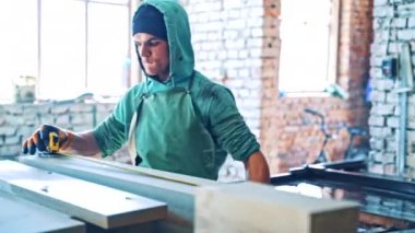 Koruyucu eldivenler ve iş kıyafetleri giyen bir adam fabrika için önlem alıyor. İşçi içeride rulet oynayarak taş levhaları ölçüyor..