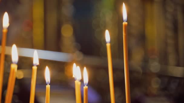 蜂蜡蜡烛在模糊的背景上闪闪发光 教堂的蜡烛在夜间寺庙里燃着 蜡烛是为祈祷而点燃的 — 图库视频影像