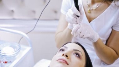 Yetenekli bir güzellik uzmanı kalıcı makyaj yapmak için patates makinesini kırmızı mürekkeple dolduruyor. Güzellik salonunda genç bir kadın için kalıcı makyaja hazırlanan kozmetolog..