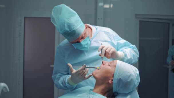医療服の歯科医は 病気の歯に麻酔注射を行っています 歯医者の診察室で女性患者を治療する組織学者 血液麻酔 — ストック動画