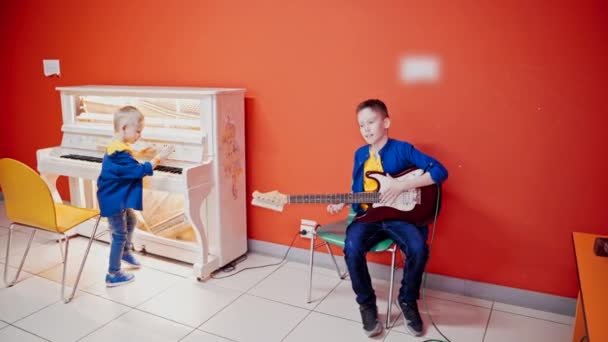 Два Счастливых Мальчика Играют Музыкальных Инструментах Фоне Красной Стены Один — стоковое видео