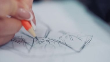 Kadın elleri şablona çizim yapıyor. Moda tasarımcısı kağıt üzerine kurşun kalemle bir elbise taslağı çizer. Çizim ve zanaat tasarımı. Yakın plan..