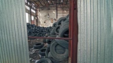 Terk edilmiş bir fabrikada bir sürü araba lastiği var. İçerideki eski fabrikanın manzarası. Yakın plan..