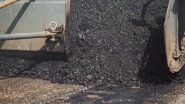 Asfalt döşeme için kamyon makinesi yola asfalt sür. Sokakta asfalt dökülmüş. Güneşli bir günde karatahta dökmek. Yol çalışması, sokak tamiri. Yakın plan. Yavaş çekim.