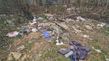 Doğada yerde yatan farklı çöpler. Bir sürü plastik şişe, arka planda bir sürü çöp. Kirlilik sorunu.